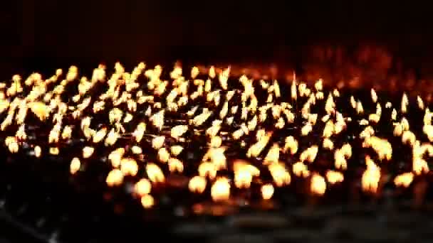 Angezündete Kerzen reihen sich aneinander und leuchten im dunklen Raum. — Stockvideo
