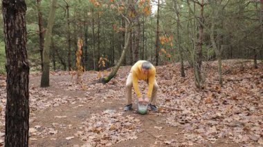 Ormanda kettlebell egzersizi yapan orta yaşlı bir adam ormanlık alanda antrenman yaparken kettlebell kullanan yetişkin bir erkek.