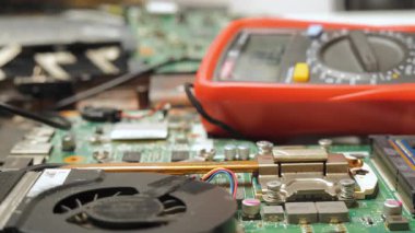 Elektronik tanılama sırasında dizüstü bilgisayardaki voltajı ölçen teknisyenler, bilgisayar üzerinde çoklu metre sondalar kullanarak elektronik devreyi test eden koruyucu eldivenlerdeki eller.