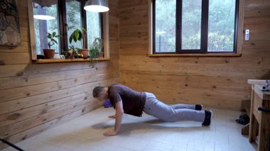 Ev antrenmanında şınav çeken adam vücut ağırlığı ve fiziksel çabayı gösteren dayanıklılık egzersizi yapıyor.