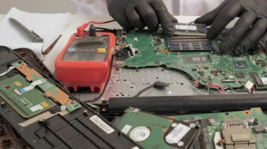 Technician repairing laptop motherboard and installing memory modules, Electronics diagnostics and maintenance with tools during hardware service