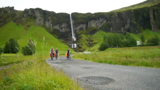 Wodospad w Sidu. Rowerzyści na tle wodospadu. Islandia. — Wideo stockowe