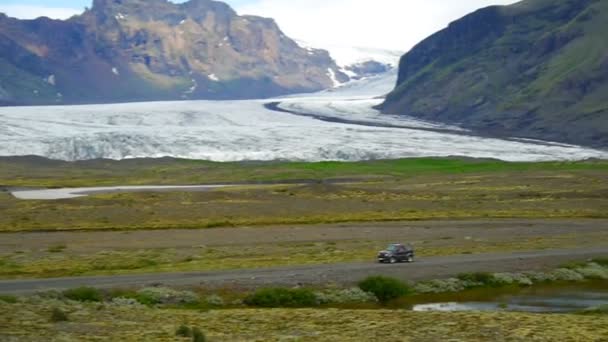 Bilen går på bakgrund av glaciären. — Stockvideo