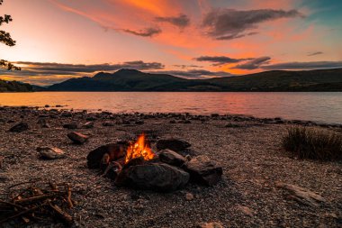 Gün batımında şömine Loch Lomond, İskoçya 'da bir gölün yanında.