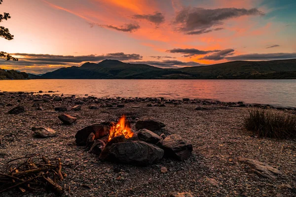 Gün batımında şömine Loch Lomond, İskoçya 'da bir gölün yanında.