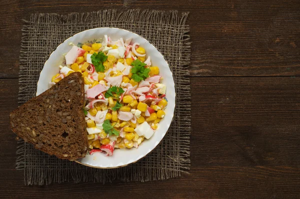 Yengeç ahşap bir masa üzerinde bir tabak salata. Rustik tarzı