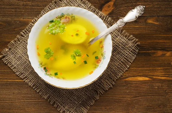 clear soup with vegetables in plate on wooden table .Rustic styl