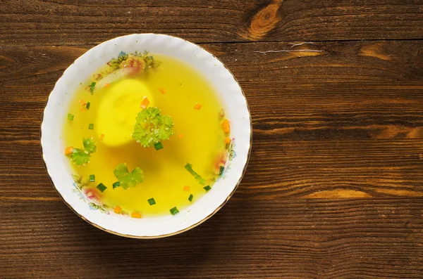 Broth with vegetables in plate on wooden table . — Stock Photo, Image