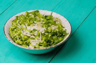 ahşap bir masa bir tabağa lahana salatası.