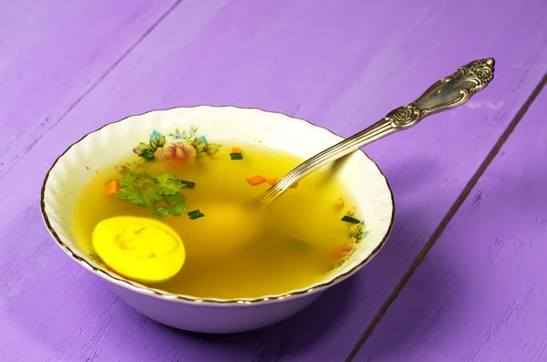 clear soup with vegetables in plate on wooden table .Rustic styl