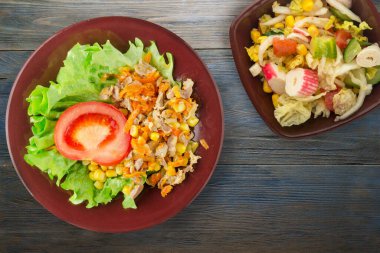 Tavuk mideli salata, havuç, mısır ve salata. Kahverengi tabak manzaralı. Mavi ahşap arka planda sebzeli tavuk salatası.