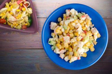 Sebze salatası manzaralı lacivert tabakta yengeç salatası. Mor ahşap arka planda yengeç salatası