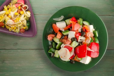 Yeşil ahşap arka planda Yunan salatası. Vejetaryen salata manzaralı yeşil tabakta Yunan salatası. sağlıklı yiyecekler