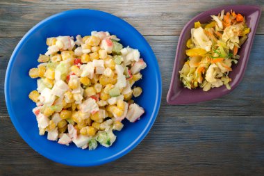 Sebze salatası manzaralı lacivert tabakta yengeç salatası. Gri ve mavi ahşap arka planda yengeç salatası