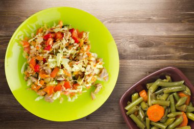 Tavuk mideli salata ile sebze havuç, soğan, biber, lahana, domates, brokoli. Kireç tabağında tavuk ve kahverengi ahşap arka planda salata. sağlıklı salatalar üst görünüm