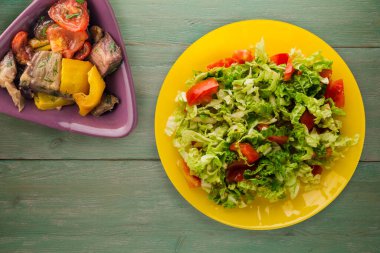 Vejetaryen yemeği. Yeşil ahşap arka planda sarı tabakta lahana domates salatası. sağlıklı yiyecekler