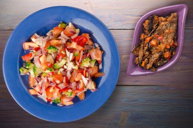 Vejetaryen yemeği. Biberli salata, domates, soğan, mavi tabakta brokoli. Mor ahşap arka planda vegan salatası