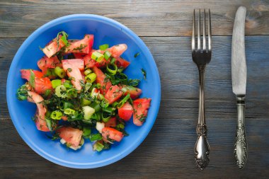 Bıçak ve çatalla vejetaryen yemeği. Domates, soğan, mavi tabakta rezene mavi gri ahşap arka planda. sağlıklı yiyecek üst görünümü