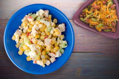 Sebze salatası manzaralı lacivert tabakta yengeç salatası. Mor ahşap arka planda yengeç salatası