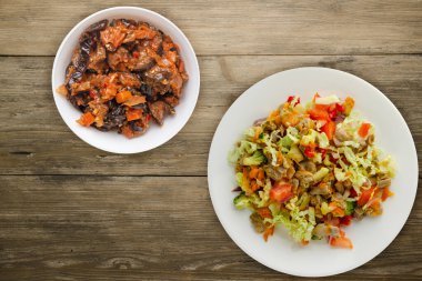 Tavuk mideli salata ile sebze havuç, soğan, biber, lahana, domates, brokoli. Tahta arka planda beyaz tabakta tavuklu salata.