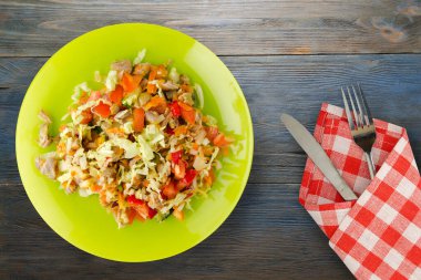 Tavuk mideli salata ile sebze havuç, soğan, biber, lahana, domates, brokoli. Mavi ahşap arka planda sarı tabakta tavuklu salata. Çatal ve bıçak manzaralı vejetaryen salatası.