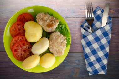  Kireç tabağında patates ve çatal ve bıçak manzaralı pirzola. Patatesli pirzola ve mor ahşap arka plan.