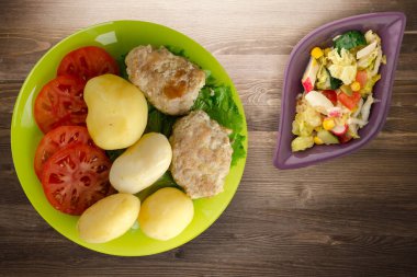  Limonlu patatesli pirzola ve sebze salatası. Kahverengi ahşap arka planda patatesli pirzola