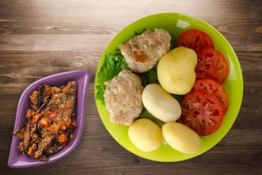 Limonlu patatesli pirzola ve sebze salatası. Kahverengi ahşap arka planda patatesli pirzola