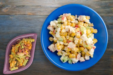 Sebze salatası manzaralı lacivert tabakta yengeç salatası. Gri ve mavi ahşap arka planda yengeç salatası