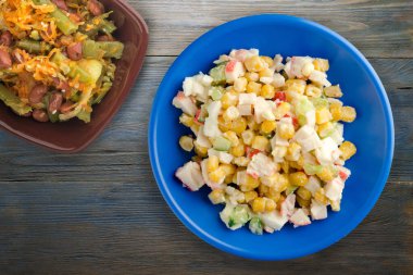 Sebze salatası manzaralı lacivert tabakta yengeç salatası. Gri ve mavi ahşap arka planda yengeç salatası