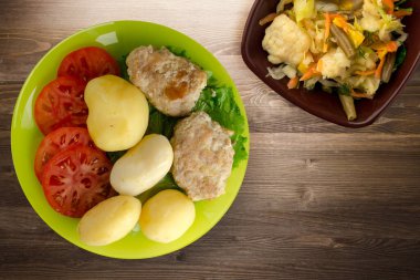 Limonlu patatesli pirzola ve sebze salatası. Kahverengi ahşap arka planda patatesli pirzola