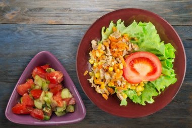 Tavuk mideli salata, havuç, mısır ve salata. Kahverengi tabak manzaralı. Mavi ahşap arka planda sebzeli tavuk salatası.