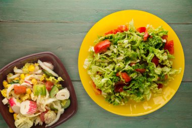 Vejetaryen yemeği. Yeşil ahşap arka planda sarı tabakta lahana domates salatası. sağlıklı yiyecekler