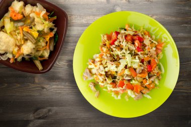 Tavuk mideli salata ile sebze havuç, soğan, biber, lahana, domates, brokoli. Limonlu tavuklu salata, siyah ahşap arka plan manzaralı.