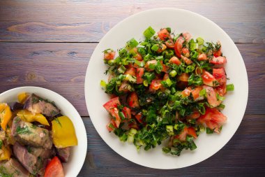 Sebze salatası manzaralı vejetaryen yemekleri. Domates, soğan, beyaz tabakta rezene mor ahşap arka planda. sağlıklı yiyecekler