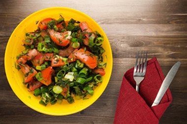 Bıçak ve çatalla vejetaryen yemeği. Domates, soğan, kahverengi ahşap arka planda sarı tabakta rezene. sağlıklı yiyecek üst görünümü