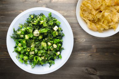 Vejetaryen yemeği. Mavi tabakta soğan ve dereotu ve siyah ahşap arka planda vejetaryen salatası. sağlıklı yiyecek üst görünümü