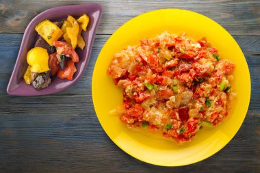 Mavi ahşap arka planda sarı tabakta soğanlı haşlanmış domates. vejetaryen yemeği