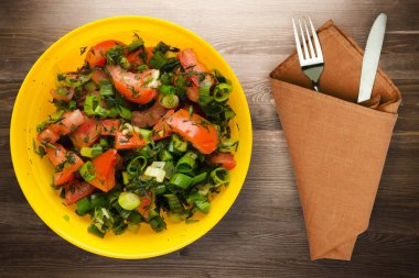 Bıçak ve çatalla vejetaryen yemeği. Domates, soğan, kahverengi ahşap arka planda sarı tabakta rezene. sağlıklı yiyecek üst görünümü