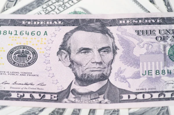Lincoln na pięć dolar nad sterty dolarów USA jako — Zdjęcie stockowe