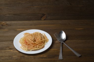 Tahta arka planda bir tabakta spagetti.