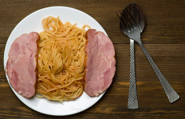 Špagety na talíři na dřevěném pozadí — Stock fotografie