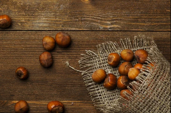 Hromadu lískových ořechů ve skořápce na dřevěný stůl — Stock fotografie
