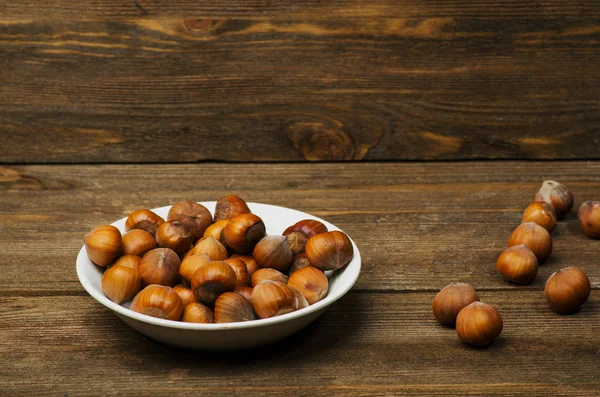 Hromada ořechů ve skořápce na dřevěný stůl — Stock fotografie