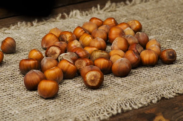 Hromadu lískových ořechů ve skořápce na dřevěný stůl — Stock fotografie