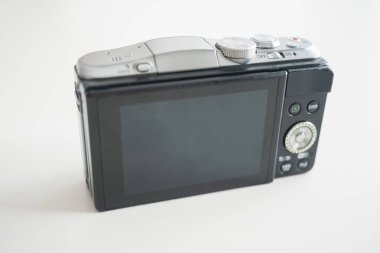 Modern görünümlü aynasız dijital bir kamera, arkası beyaz bir masaya bakıyor.