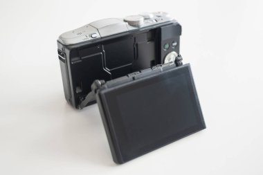 Beyaz bir masanın üzerine eklemli ekran yerleştirilmiş modern tasarım aynasız dijital kamera.