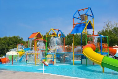 Parkta havuzu olan çocuklar için kaydıraklar. Çocuklar için su parkı olan bir tatil köyü. Yaz tatili. Açık hava aktivitesi.