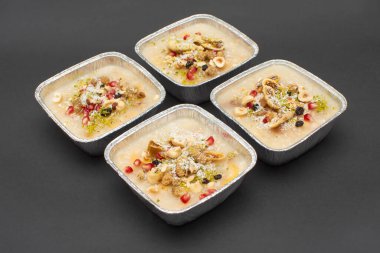 Siyah zemin üzerinde izole edilmiş tek kullanımlık alüminyum kasede geleneksel Türk Tatlı Güvencesi veya Ashura (diğer adıyla Nuh Pudingi) yakın plan. 