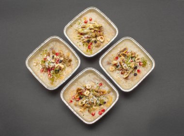 Siyah zemin üzerinde izole edilmiş tek kullanımlık alüminyum kasede geleneksel Türk Tatlı Güvencesi veya Ashura (diğer adıyla Nuh Pudingi) yakın plan. 